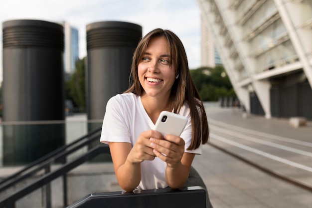 Portret pozuje smiley kobiety podczas gdy trzymający jej telefon