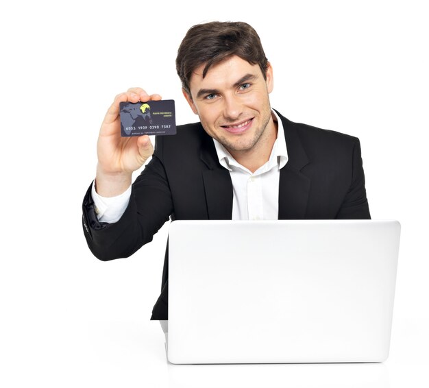 Portret pracownika biurowego z laptopa i karty kredytowej, siedząc na stole na białym tle.