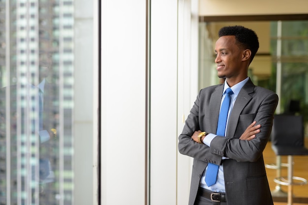 Portret Przystojnego Afrykańskiego Biznesmena Patrzącego Przez Okno Podczas Myślenia Premium Zdjęcia