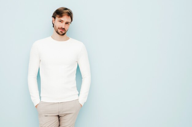 Portret przystojnego uśmiechniętego hipstera drwala modelu biznesmena noszącego dorywczo biały sweter i spodnie