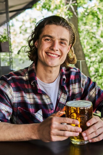 Portret przystojny mężczyzna pije piwo w pubie.