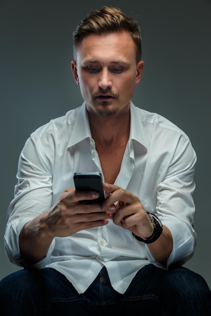 Bezpłatne zdjęcie portret przystojny mężczyzna w białej koszuli z telefonem komórkowym.