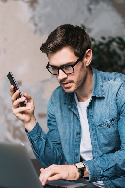 Portret Przystojny Młody Człowiek Używa Laptopu Mienia Telefon Komórkowego