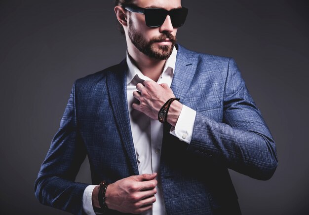 Bezpłatne zdjęcie portret przystojny moda model hipster stylowy biznesmen biznesmen ubrany w elegancki niebieski garnitur pozowanie na szaro