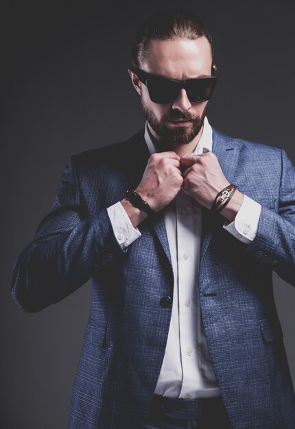 portret przystojny moda model hipster stylowy biznesmen biznesmen ubrany w elegancki niebieski garnitur pozowanie na szaro