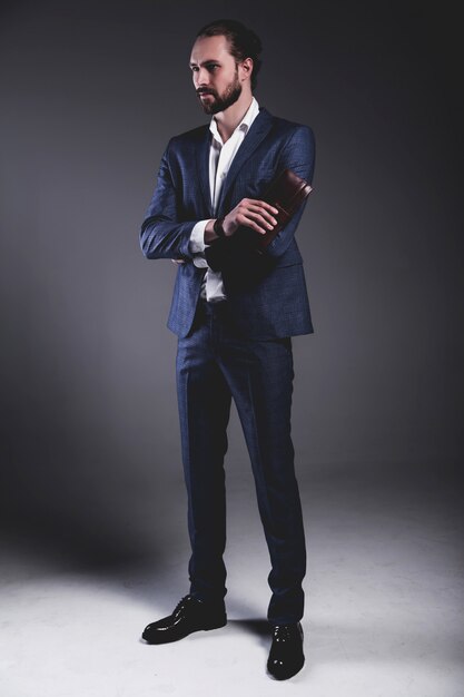portret przystojny moda model hipster stylowy biznesmen biznesmen ubrany w elegancki niebieski garnitur pozowanie na szaro