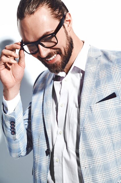portret przystojny moda stylowy hipster biznesmen model ubrany w elegancki jasnoniebieski garnitur w okularach na białym tle.
