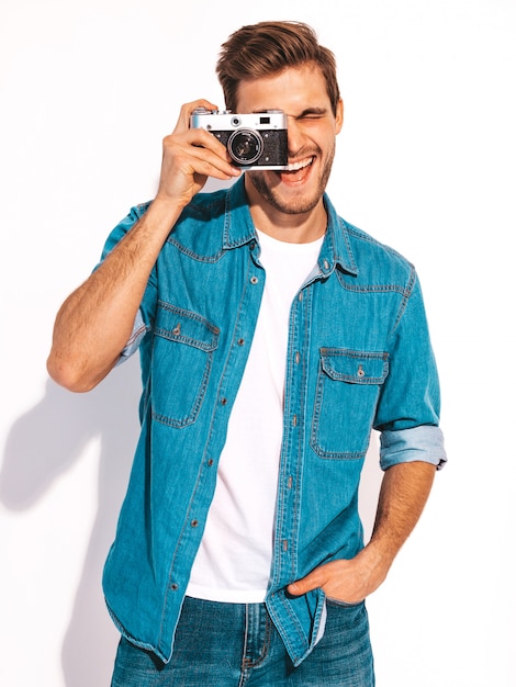 Bezpłatne zdjęcie portret przystojny uśmiechnięty mężczyzna jest ubranym lato cajgi odziewa. wzorcowa samiec bierze obrazek na starym rocznik fotografii kamerze.