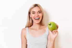 Bezpłatne zdjęcie portret radosna dziewczyna w bieliźnie pokazuje zielonego jabłka