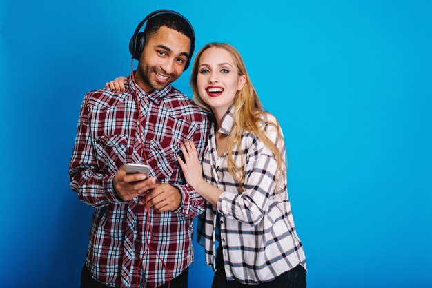 Portret radosna para atrakcyjna młoda kobieta z długimi blond włosami, zabawy wraz z przystojnym facetem, słuchanie muzyki przez słuchawki. Wesoły nastrój, uśmiechnięty.
