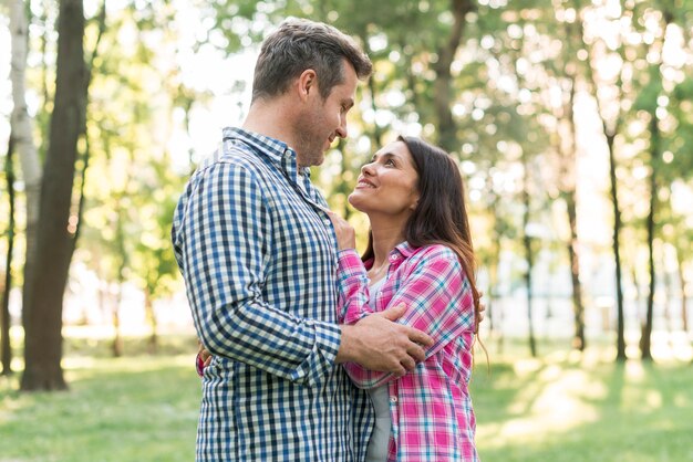 Portret romantyczna para patrzeje each inny podczas gdy obejmujący w parku