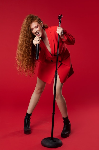 Bezpłatne zdjęcie portret rudowłosej śpiewającej kobiety z mikrofonem