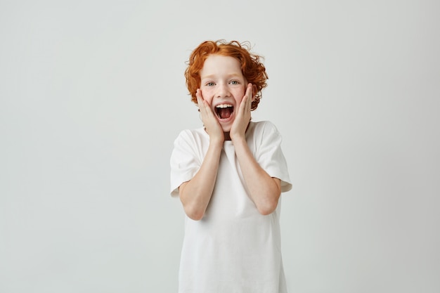 Portret śliczny czerwony z włosami dziecko krzyczy z szczęśliwym wyrażeniem