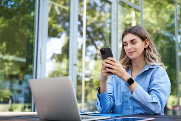 Portret sprzedawczyni pracującej poza biurem z laptopem za pomocą telefonu komórkowego cyfrowego koczownika w