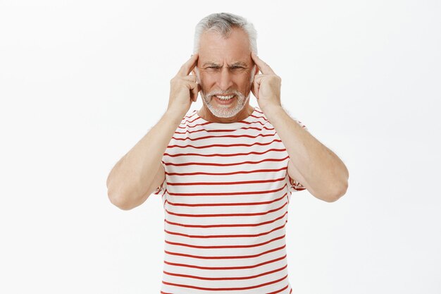 Portret starego brodatego mężczyzny dotykającego głowy, skarżącego się na ból głowy, ma migrenę