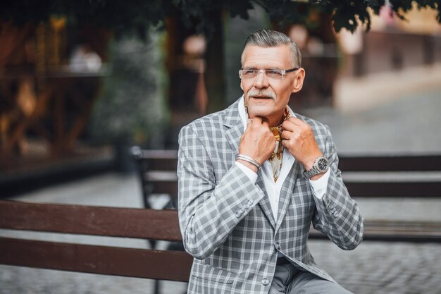 Portret starego brodatego mężczyzny w szarym płaszczu, skrzyżowane ramiona, czekając na uśmiech. Skopiuj miejsce po lewej stronie