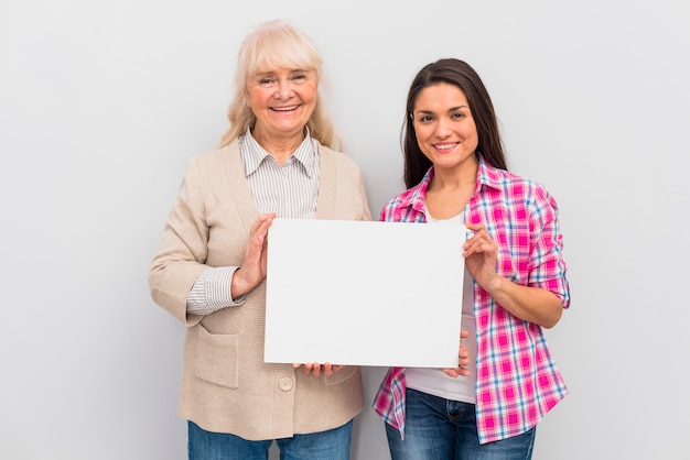 Portret starsza kobieta i jej córka pokazuje pustego białego plakat