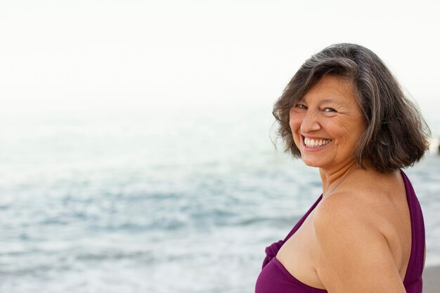 Portret starszej uśmiechniętej kobiety na plaży