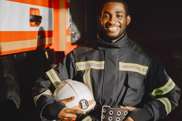 Portret strażaka stojącego przed wozem strażackim