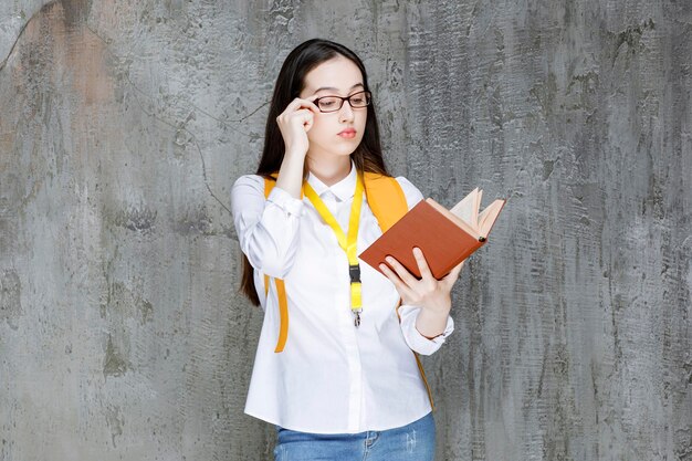 Portret studentki w okularach, czytanie książki. Zdjęcie wysokiej jakości