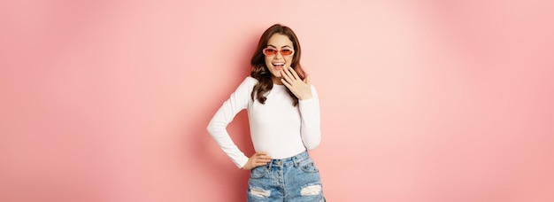 Portret Stylowej Glam Dziewczyny W Okularach Przeciwsłonecznych śmiejącej Się I Uśmiechającej Stojącej Nad Wakacyjnym Różowym Tłem