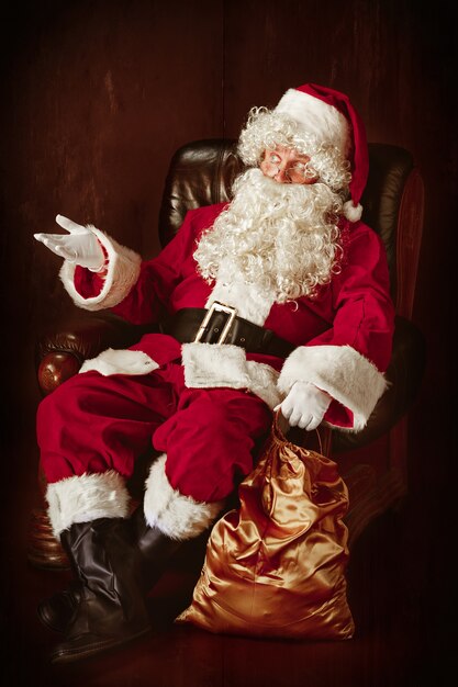 Portret Świętego Mikołaja w czerwonym kostiumie siedzi w fotelu