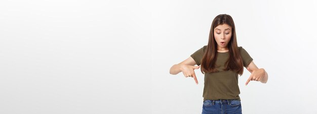 Portret szczęśliwa i zaskoczona młoda dama stojąca na białym tle nad szarym tłem patrząca na kamerę pointi