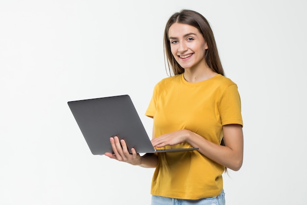 Portret szczęśliwa kobieta pracuje na laptopie odizolowywającym nad biel ścianą