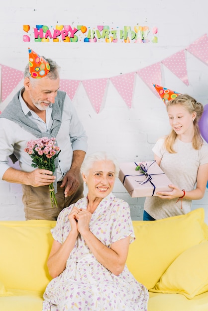 Portret szczęśliwa kobieta przed mężem i wnuczką z urodzinowymi prezentami