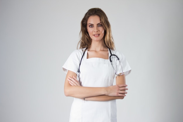 Portret szczęśliwa młoda kobieta lekarz stoi, odizolowane na białym tle.