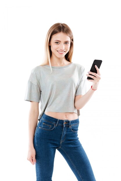 Portret szczęśliwa młoda kobieta stoi telefon komórkowego i trzyma