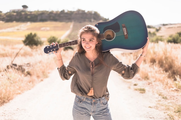 Portret szczęśliwa nastoletniej dziewczyny mienia gitara przy outdoors