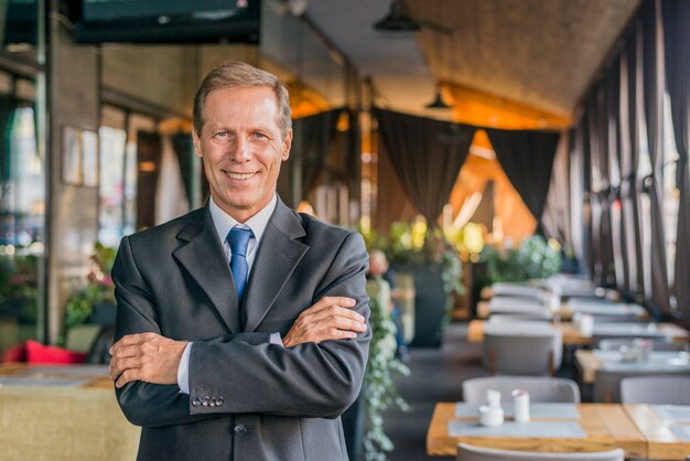 Portret szczęśliwa pomyślna biznesmen pozycja w restauraci z krzyżującą ręką