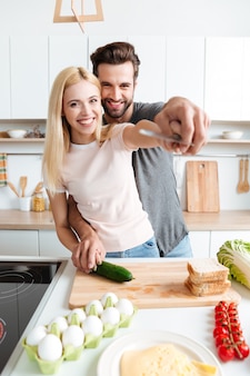 Portret szczęśliwa potomstwo para gotuje wpólnie w kuchni