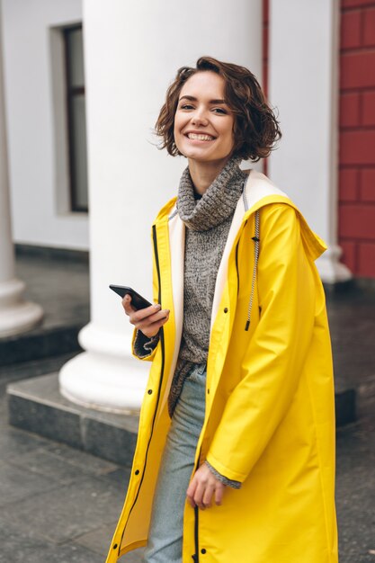 Portret szczęśliwa radosna kobieta spaceruje ulicą opowiada na jej telefonie komórkowym satysfakcjonuje z dobrą wiadomością