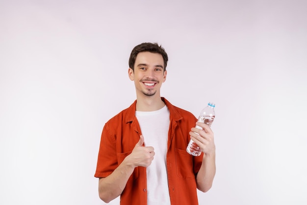 Portret szczęśliwego młodego człowieka pokazującego wodę w butelce odizolowywającej nad białym tłem