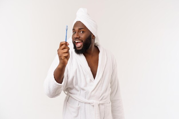 Portret szczęśliwego młodego darkanma myjącego zęby czarną pastą do zębów na białym tle