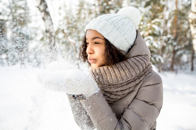 Portret szczęśliwej dziewczyny dmuchanie śniegu w zimie