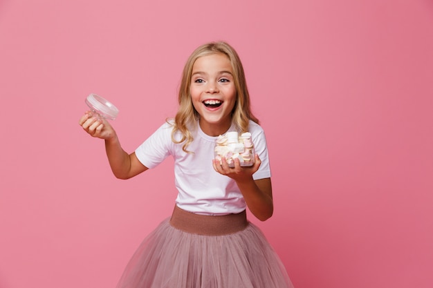 Portret szczęśliwej małej dziewczynki mienia otwarty słój marshmallow