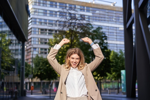 Bezpłatne zdjęcie portret szczęśliwej młodej bizneswomanu podnosi ręce do góry robi pompę pięściową świętuje zwycięstwo wygrywa coś achi