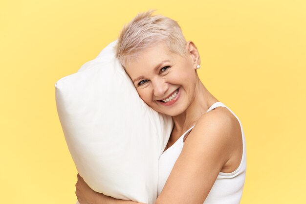 Portret szczęśliwej pięknej kobiety w średnim wieku z włosami koszuli o energicznym wyglądzie z powodu pełnego snu na wygodnej białej poduszce z pianki memory.