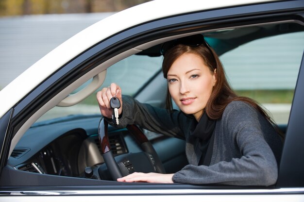 Portret szczęśliwej udanej kobiety z kluczami od nowego samochodu - na zewnątrz