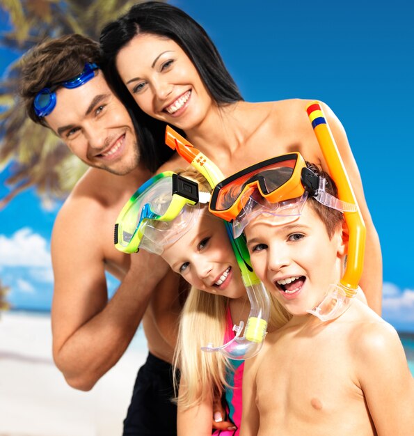 Portret szczęśliwej zabawy pięknej rodziny z dwójką dzieci na tropikalnej plaży z ochronną maską do pływania