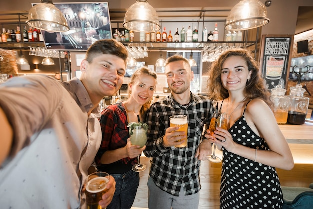 Portret szczęśliwi przyjaciele z napojami przy pubem