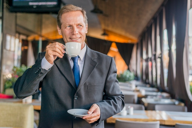 Portret szczęśliwy biznesmen pije kawę w restauraci