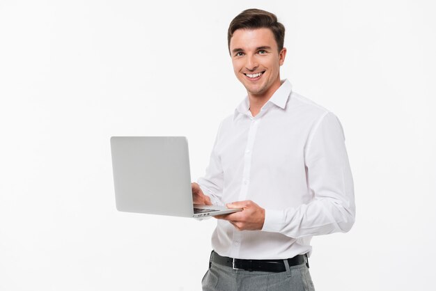 Portret szczęśliwy młodego człowieka mienia laptop