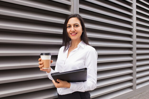 Portret szczęśliwy młody bizneswoman z takeout kawą