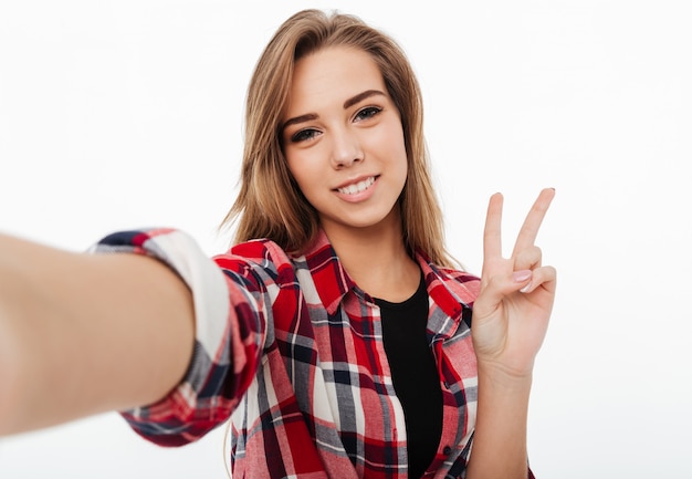 Portret szczęśliwy pięknej dziewczyny w kraciastej koszuli przy selfie