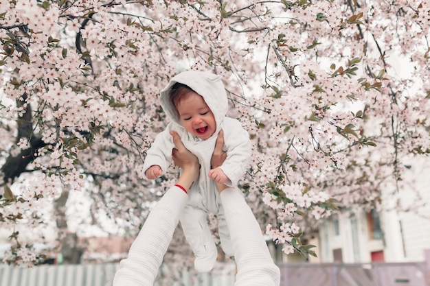 Portret szczęśliwy radosny dziecko w biel ubraniach nad drzewnymi kwiatami kwitnie tło.