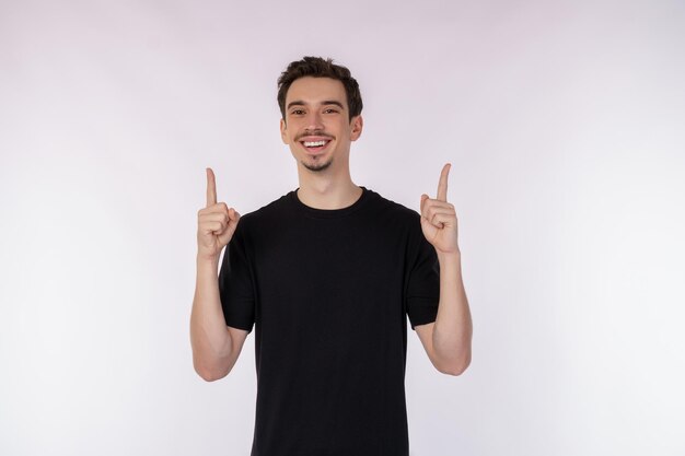 Portret szczęśliwy uśmiechnięty młody człowiek pokazuje aprobaty gest i patrzeje kamerę na odosobnionym nad białym tłem
